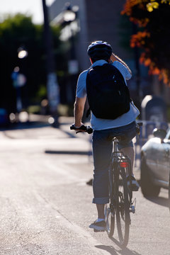 Man Cyclist Rides Towards The Sun On Street Of Urban City