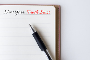 Conceptual,notebook on a white table. open diary and pen with new year...fresh start words