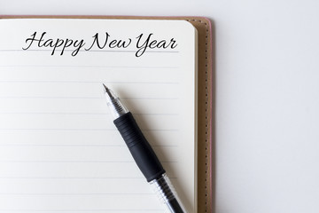 Conceptual,notebook on a white table. open diary and pen with happy new year words