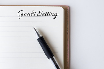 Conceptual,notebook on a white table. open diary and pen with goals setting words