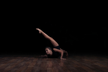 Fototapeta na wymiar Flexible girl doing a gymnastic exercise on a black background. Sport. Fitness. Stretching.