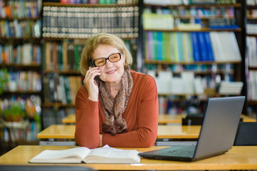 senior woman using mobile phone in library