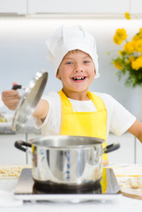 Happy little boy opened the lid on the pan