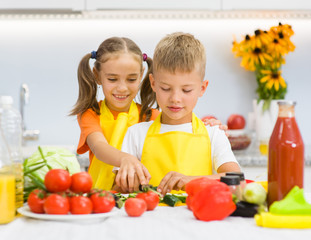 Children cut cucumbers for vegetable salad