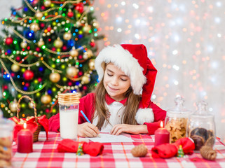 Little girl in red christmas hat writes letter to Santa Claus