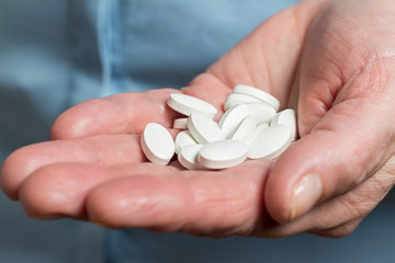 White medication pills, calcium dietary supplement in the woman palm hand