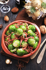 Brussels sprouts with bacon, and caramelised onion on a black rustic table. Christmas table setting ideas. New Year food concept.