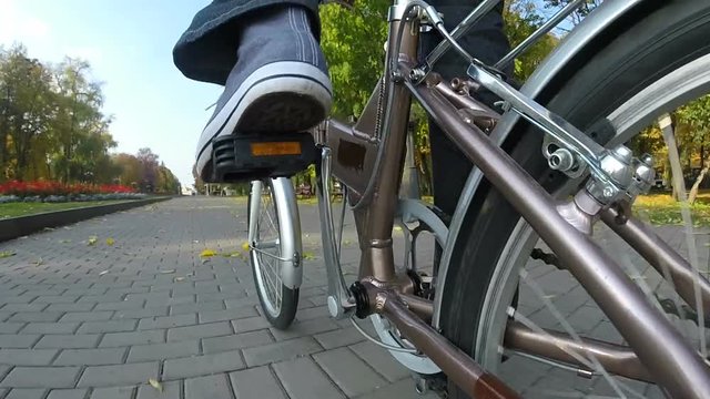 

 Man  goes by bicycle on autumn park with yellow leaves. Point of view camera filming
