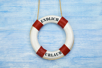 Rettungsring vor blauem Hintergrund beschriftet Endlich Urlaub