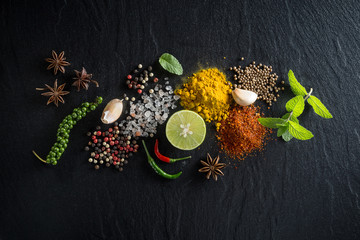 Flat-lay of spices and herbs on black background. Ingredients for cooking. Food background on stone. Top view copy space