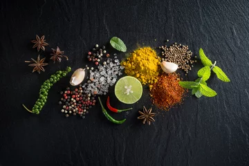 Wall murals Aromatic Flat-lay of spices and herbs on black background. Ingredients for cooking. Food background on stone. Top view copy space