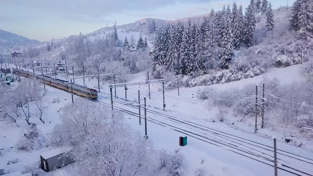 Aerial view of the train going through the mountainous terrain in winter