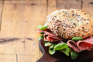 Bagels with salami and onion on a wooden board with free text space. Selective focus.