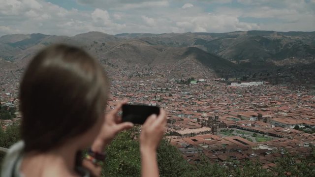 Tourist woman taking travel picture with camera, overview city Cuzco.View from the back.