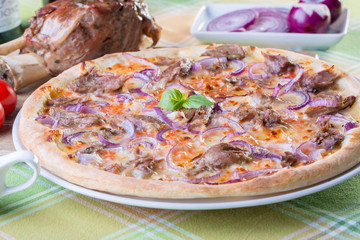 close up of italian pizza with pork meat and onions