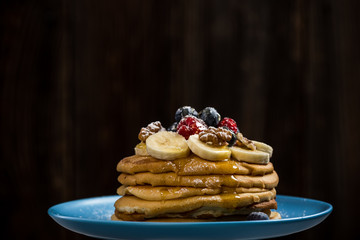 Decorated pancakes on plate with honey and berries.