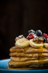 Decorated pancakes on plate with honey and berries.