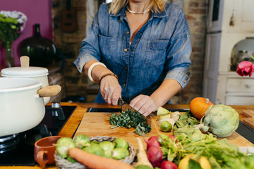Cheerful woman chopping vegetables on kitchen
