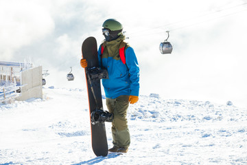 Winter sports concept - male snowboarder holding his snowboard at the top of a mountain - outdoors...