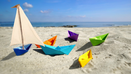 Papierboote mit Segel am Strand