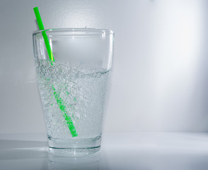 Grüner Strohhalm im Wasserglas auf weiss