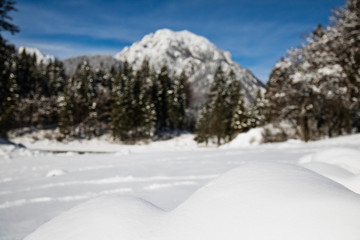 alpine mountain pass winter scenery landscape by lake lago del predil in sunny blue sky in snowfall, italy