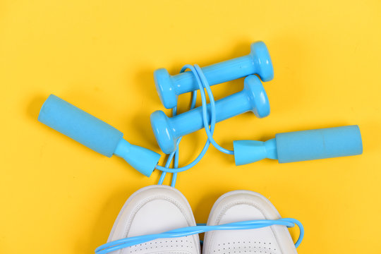 Dumbbells in cyan blue color on white trainers, top view