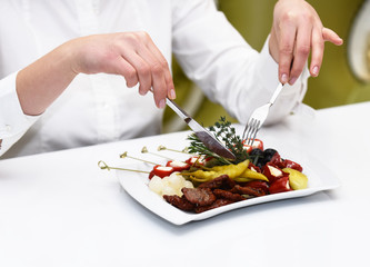 Female hands with knife and fork cutting pickled pepper.