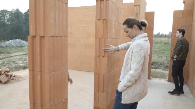 Family talking anch cecking walls at construction site of their home

