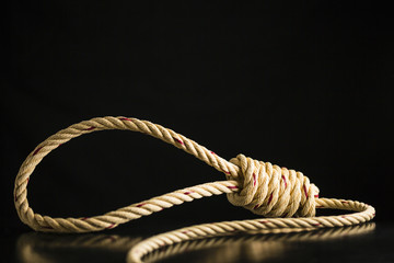 Brown rope noose dark and light on black table with black background, concept of hanging suicide