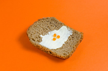 A piece of black rye bread, smeared with butter and red caviar