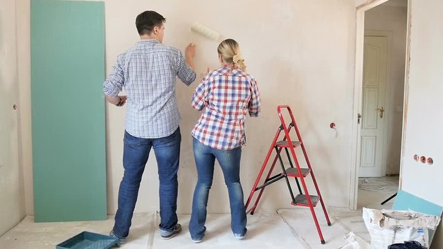 Slow motion footage of happy cheerful couple dancing while painting walls