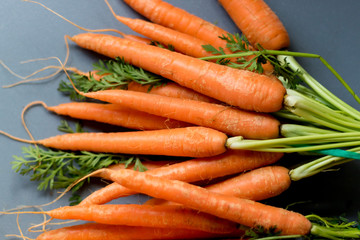 Carrots on chopping board with green stems