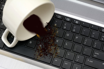 Coffee spilled out of Cup on Laptop Keyboard damage concept