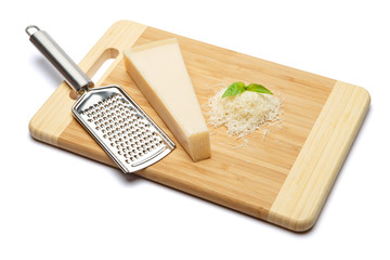 a piece of Parmesan and grated cheese on cutting board white background
