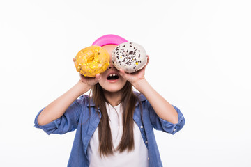 Little girl playing with two sugar donut with toppings putting them like eyes smiling in white background