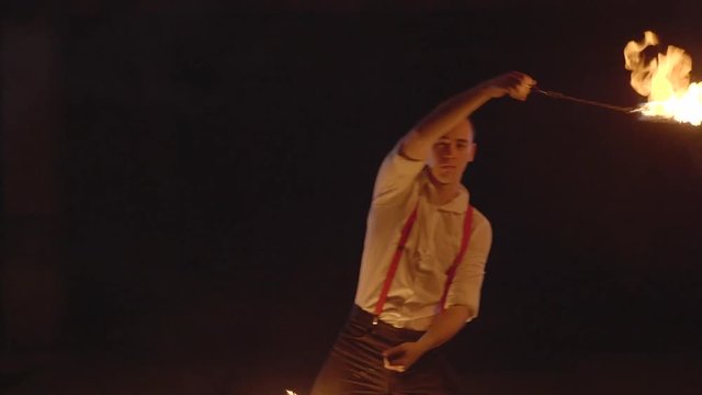 Male artist performing fire show at dark in slow motion.