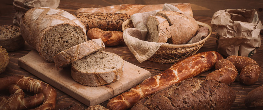 Various baked breads and rolls on rustic wooden table