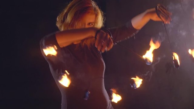 Yong woman artist performing fire show at dark in slow motion.