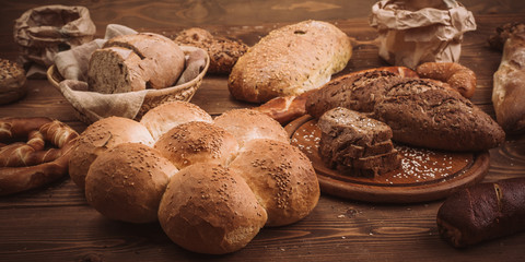 Various baked breads and rolls on rustic wooden table