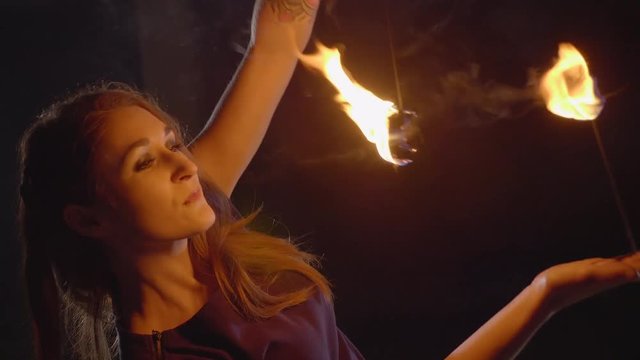 Yong woman artist performing fire show at dark in slow motion.
