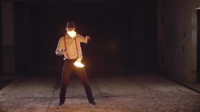 Male artist performing fire show at dark in slow motion.