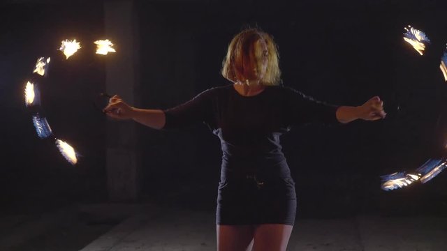 Yong woman artist performing fire show at dark in slow motion.