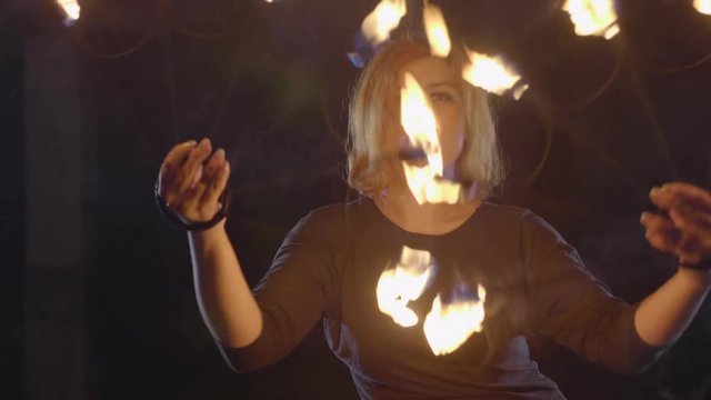 Yong woman artist performing fire show at dark in slow motion.