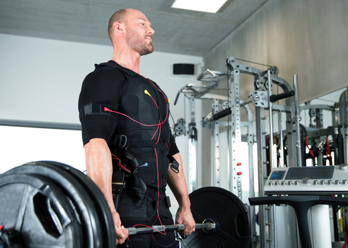 junger muskulöser mann traininert im fitness studio center seine sportübungen mit einem elektrostimulations gerät strom impuls ems elektromyostimulation Kreuzheben