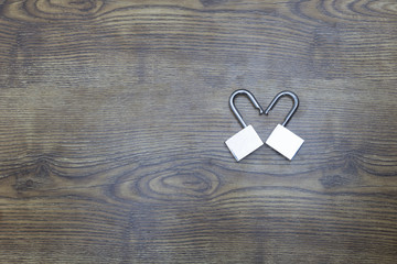 Two locks in shape of heart on wooden table. Top view. Symbol of Valentine's day.