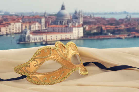 Image of elegant venetian mask on silk fabric in front of blurry Venice background