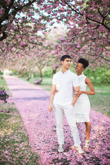 Fototapeta premium The young happy romantic couple standing on the road with petals in the park