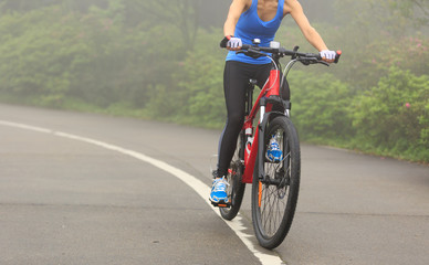Young woman cyclist riding mountain bike on trail