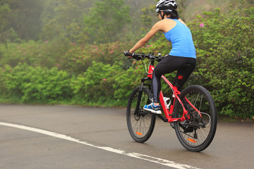 Young woman cyclist riding mountain bike on trail